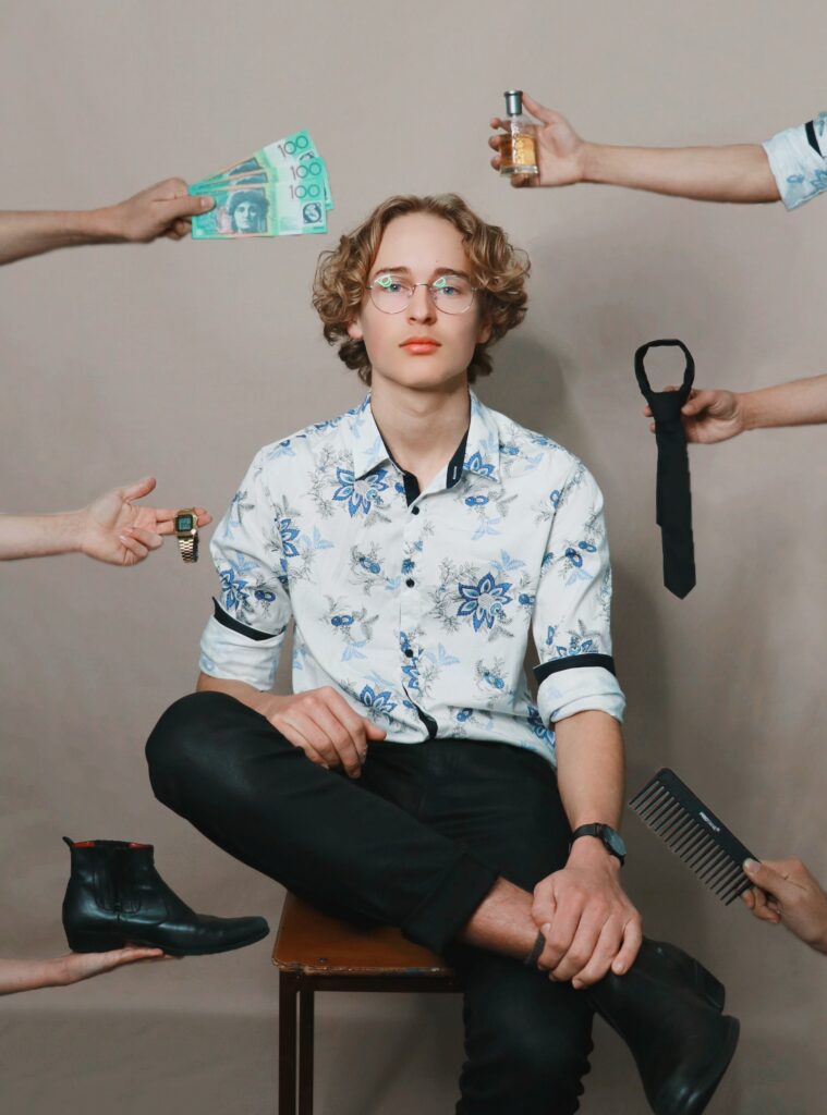 Jeune homme avec des mains autour de lui lui tendant des objets comme de l'argent, une cravate, une chaussure
